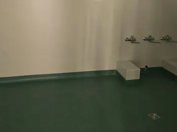 Bagno d’asilo con rubinetti bassi e pavimento in linoleum verde acqua